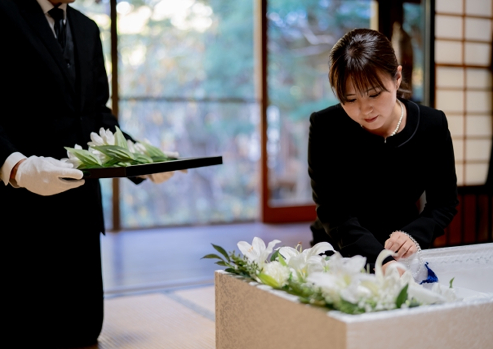 メモサのお葬式が松戸市で白い花を飾り直葬の棺に納棺準備をしている
